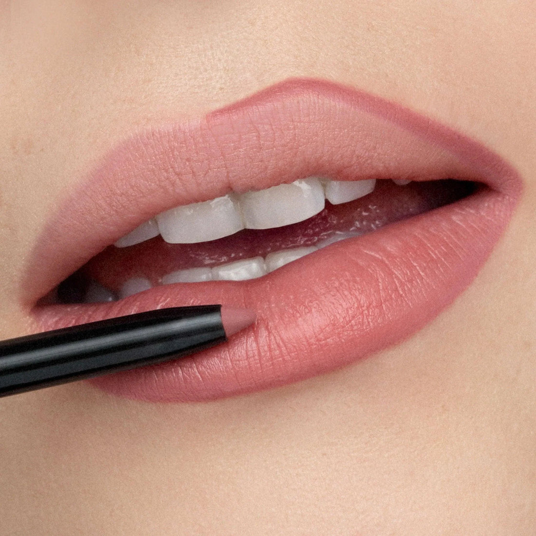 Close-up of natural pink lips being softly defined with a mauve lip liner, creating a subtle and polished everyday makeup look.